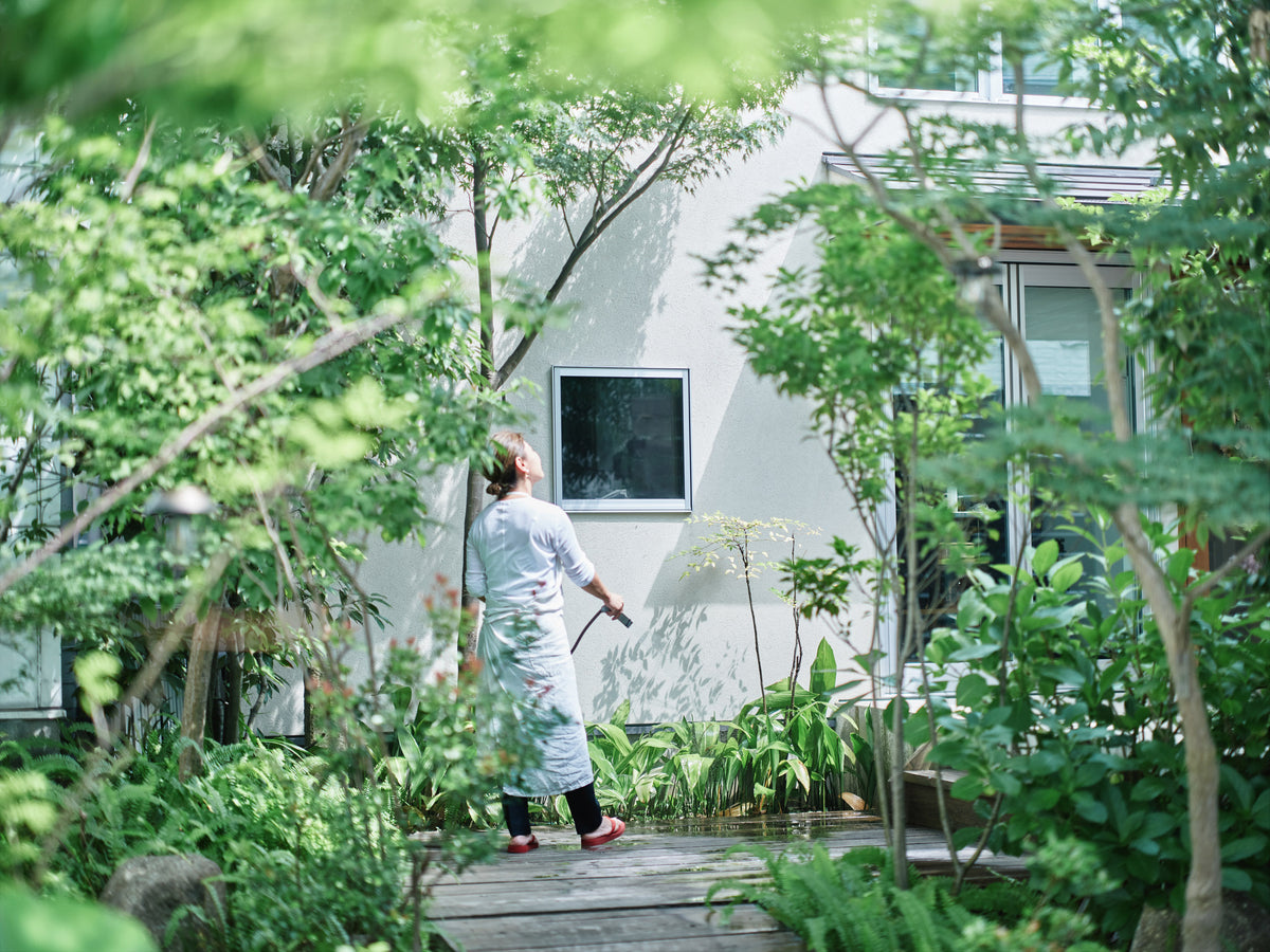 木々に囲まれた庭で植物に水をやる平林愛