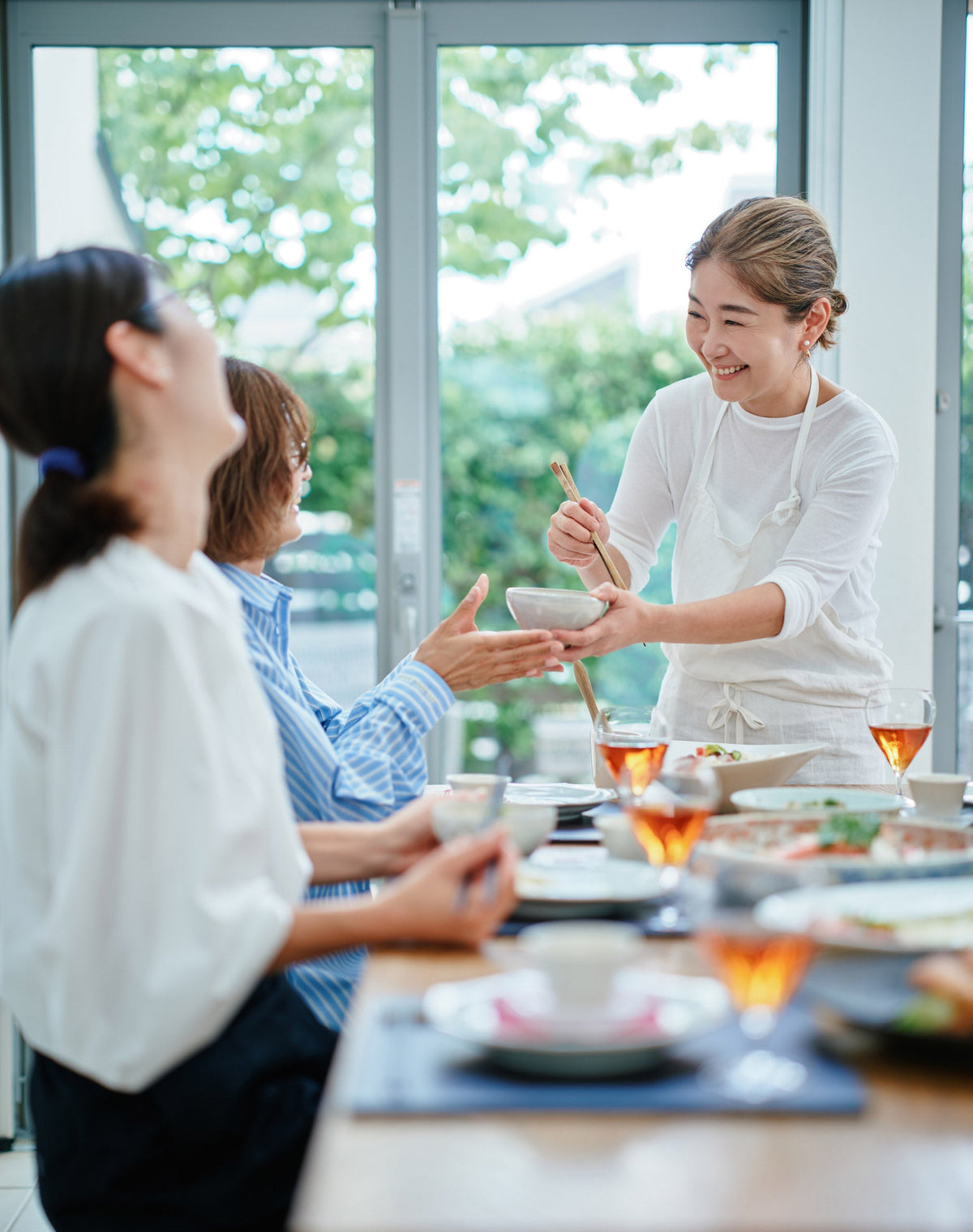 生徒と食卓を囲み料理を取り分ける料理家 平林愛